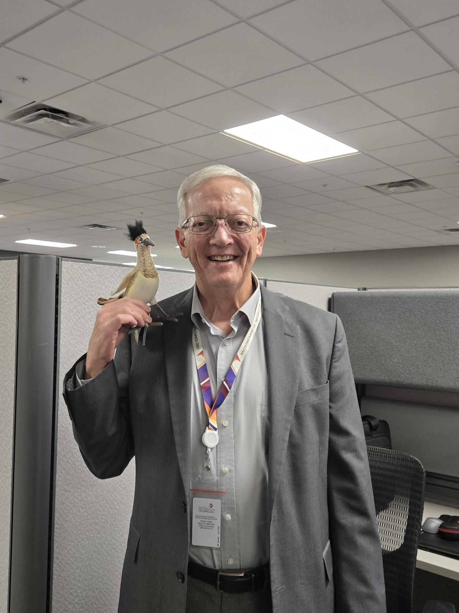 David Dikitolia standing in his office with the roadrunner award perched on his finger tips.