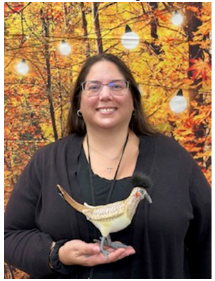 Leslie Trujillo standing in front of a fall backdrop holding the road runner award in her hand.