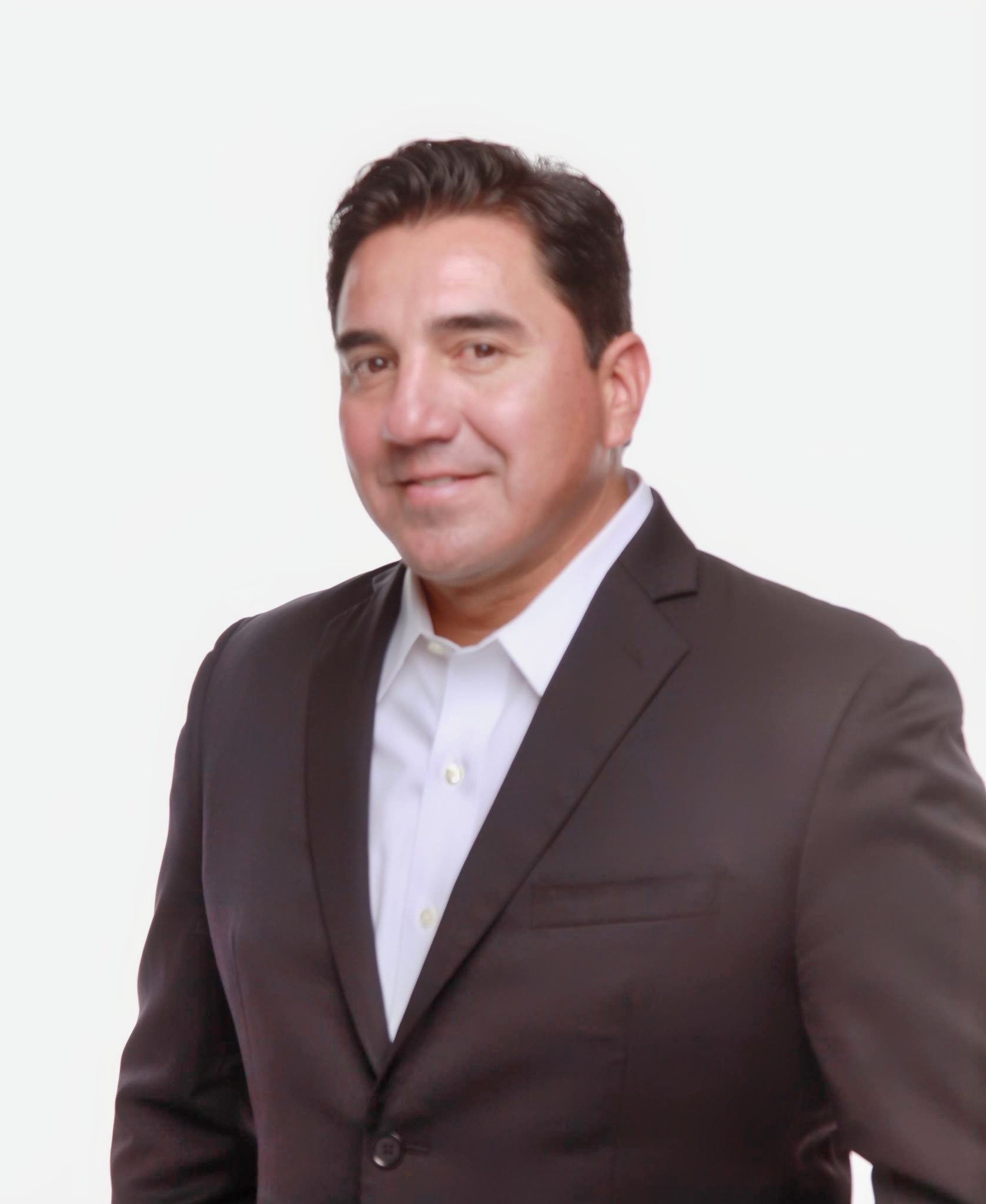 Headshot of Manny Barreras wearing a suit and smiling.